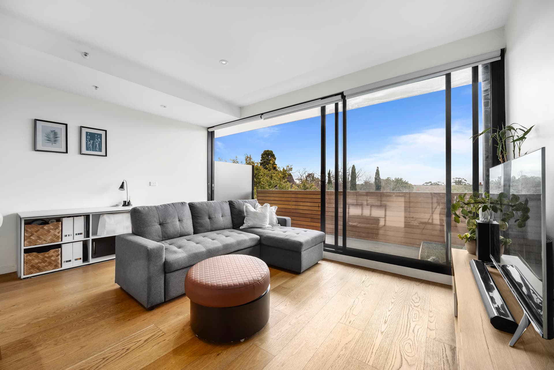 A sunlit Malvern East apartment living room opening to a balcony