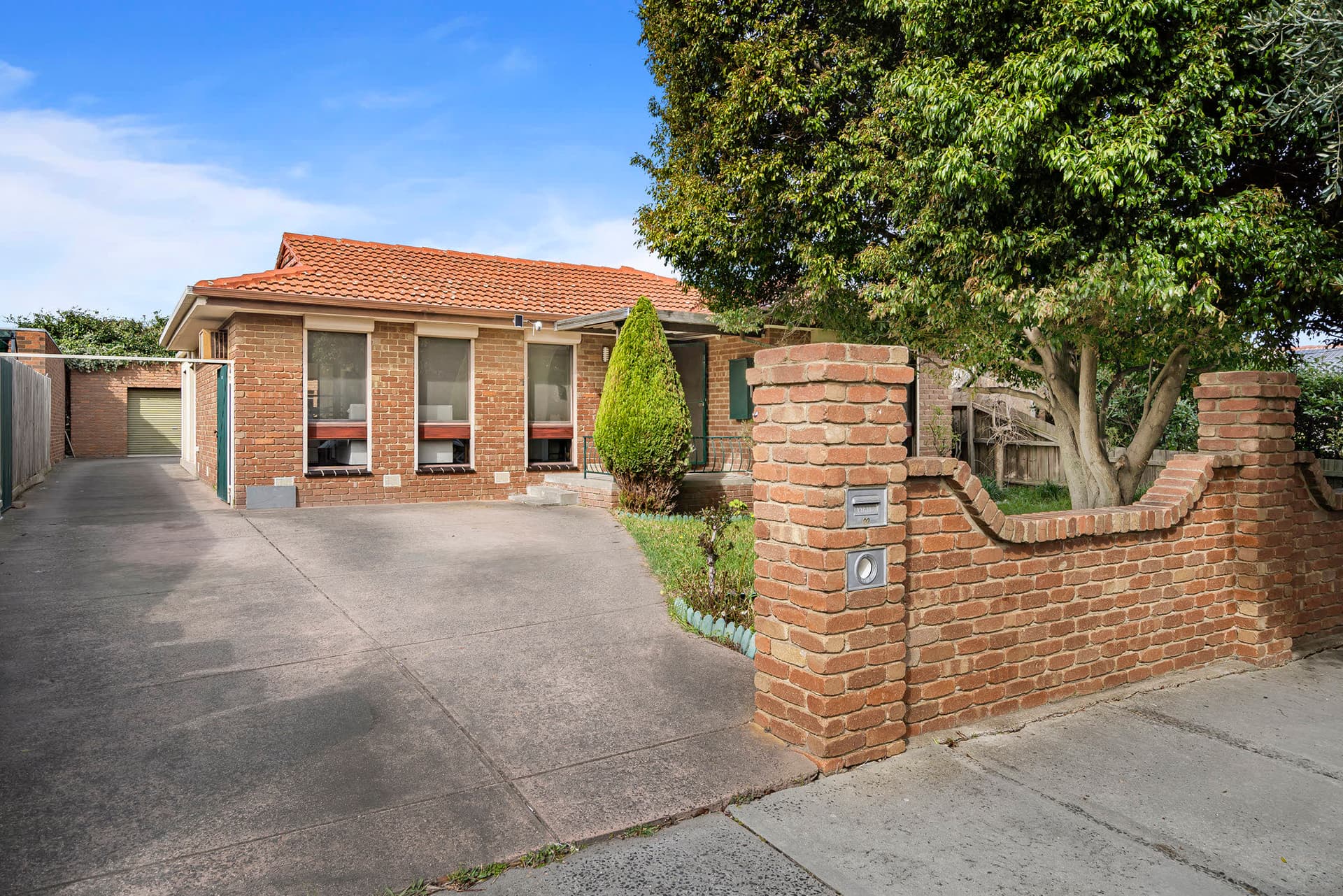A brick family home with a front garden and driveway